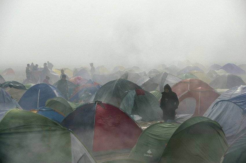 People walk among tents during foggy a morning at a makeshift camp at the Greek-Macedonian border near the Greek village of Idomeni where thousands of refugees and migrants are stranded on March 8, 2016.  European Union leaders on March 7 hailed a "breakthrough" in talks with Turkey on a deal to curb the migrant crisis but delayed a decision until a summit next week to flesh out the details of Ankara's new demands. More than one million refugees and migrants have arrived in Europe since the start of 2015 -- the majority fleeing the war in Syria -- with nearly 4,000 dying while crossing the Mediterranean. / AFP / DIMITAR DILKOFF